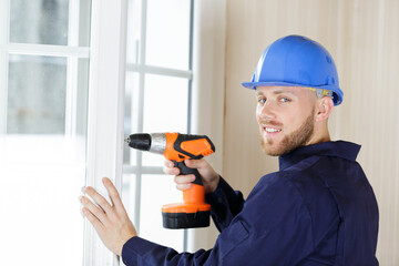 portrait of construction worker using drill on double-glazed window