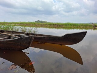 Tranquil Scene of Canoes Reflected on Calm Water Under Cloudy Sky