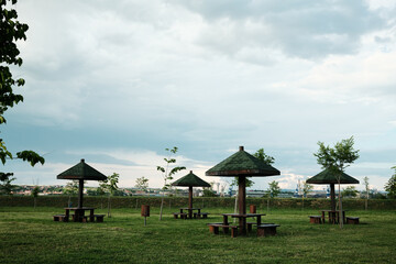 Park scene with five picnic shelters on a grassy field under a cloudy sky. Serbian town Kladovo.