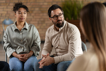 Diverse people sitting in circle sharing problems during group therapy session