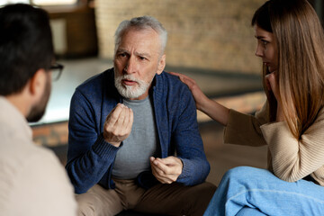 Senior man talking with psychologist and supporting woman during therapy session