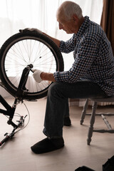 Active senior male cyclist checking bike wheel doing maintenance routine fixing with wrench....