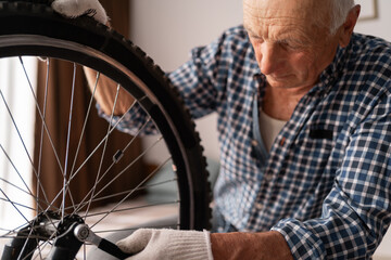 Active senior male cyclist checking bike wheel doing maintenance routine fixing with wrench....