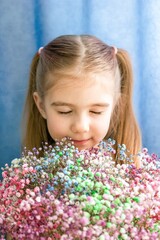 Little Girl with Flowers. Portrait of Child with Closed Eyes Enjoying Colorful Bouquet.