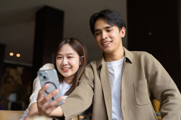 portrait of a happy young couple taking selfie in cafe with mobile phone