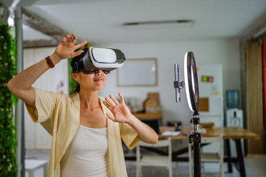 Japanese woman filming online content with smart phone wear VR goggles - Powered by Adobe