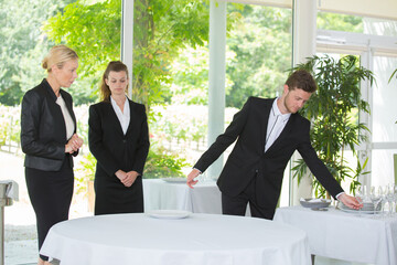manager watching waiter set restaurant table