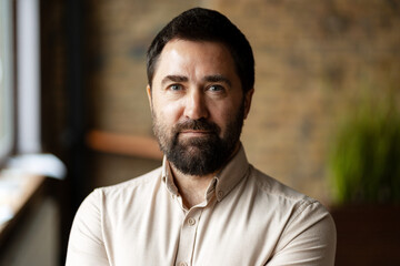 Confident businessman posing in modern office with arms crossed