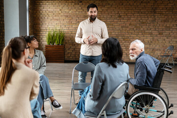 Male therapist speaking to diverse group during a group therapy session