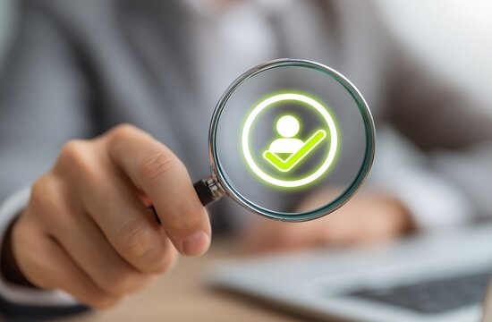 High quality photo of businessman meticulously ends an employee's task with a green check mark icon on a virtual screen, using a magnifying glass and hand focus. The business person.