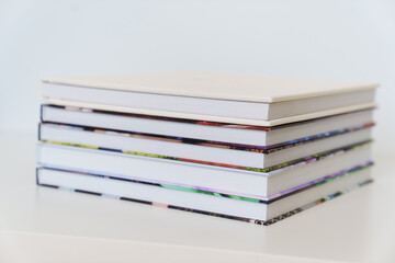 Folded photo books with white leather and multi-colored photo covers.