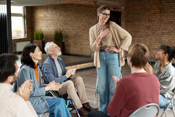 Grateful woman receiving applause from support group members during rehab therapy session