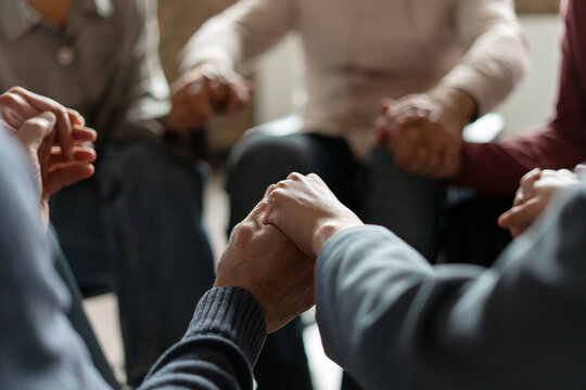 People holding hands supporting each other during group therapy session