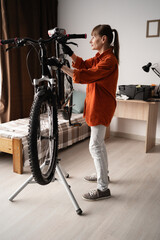 Female cyclist prepares bike for summer season by repairing bicycle at home