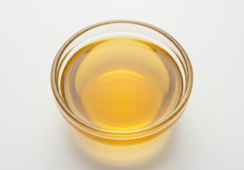 Clear bowl filled with golden liquid, viewed from above on white background