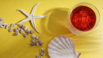 Cold refreshing summer beverage, strawberry or cranberry drink with ice cubes, several seashells,...