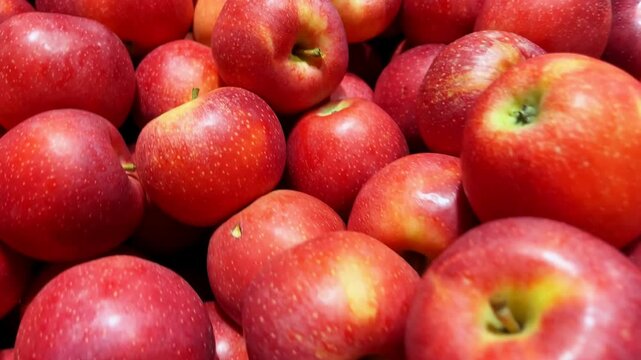 A close-up shot of a pile of fresh, crisp, and shiny red apples at a market. A classic symbol of health, nutrition, and the autumn harvest.