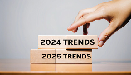 Hand placing wooden block with 2024 trends on top of 2025 trends