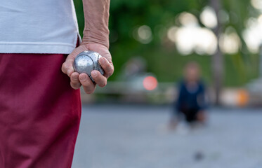 back view senior man hand holding boules to throw in playing field on blurred background petanque...