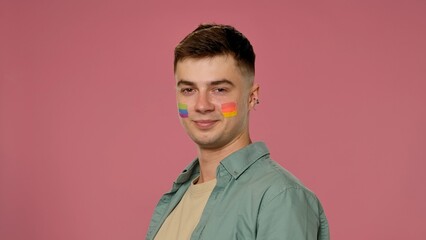 Man with Rainbow Face Paint Smiling Against Pink Background
