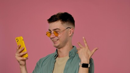 Young Man Taking Selfie with Yellow Phone in Stylish Glasses