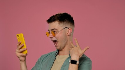 Excited Young Man with Smartphone on Pink Background