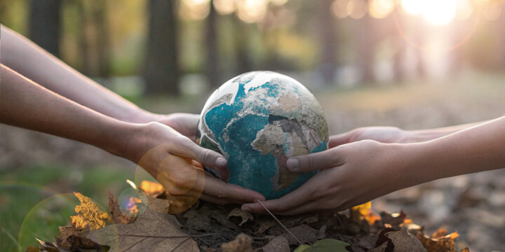 World Environment Day. Two hands holding a miniature world carefully on autumn leaves in the forest represent love for earth care for the environment and protection of nature