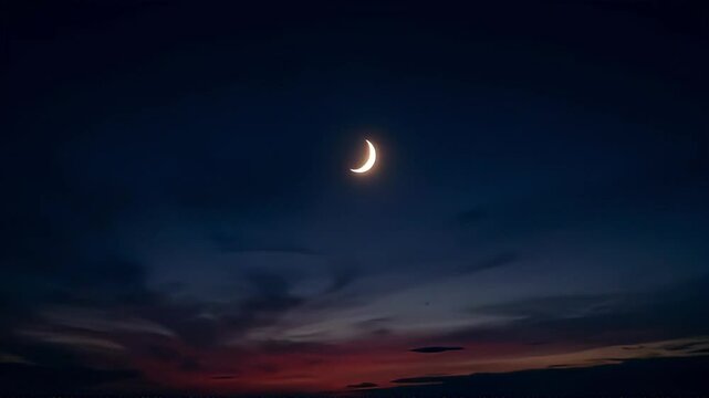 Serene crescent moon graces the twilight sky, painting a breathtaking scene with orange hues during evening hours.