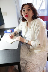 Businesswoman writing notes at desk in office environment