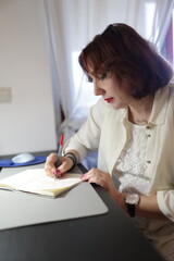 Businesswoman writing notes in notebook at office desk