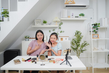 Two beautiful professional asian young woman blogger recording vlog video with make up cosmetic at home online influencer on social media concept. Live streaming viral 