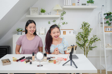 Two beautiful professional asian young woman blogger recording vlog video with make up cosmetic at home online influencer on social media concept. Live streaming viral 