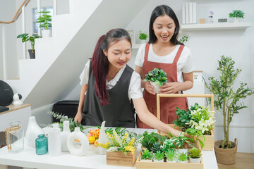 Small business. Two young asia woman florist smile arranging flowers in floral shop. Flower design store. Happiness smiling young female making flower vase for customers. 