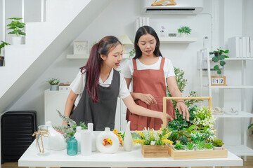 Small business. Two young asia woman florist smile arranging flowers in floral shop. Flower design store. Happiness smiling young female making flower vase for customers. 