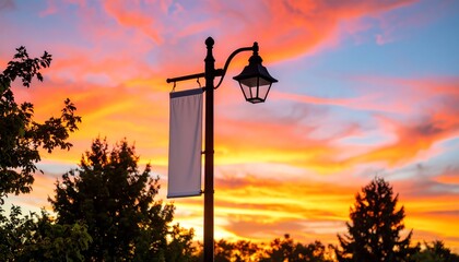 Obraz premium Street lamp illuminating a vibrant sunset sky.