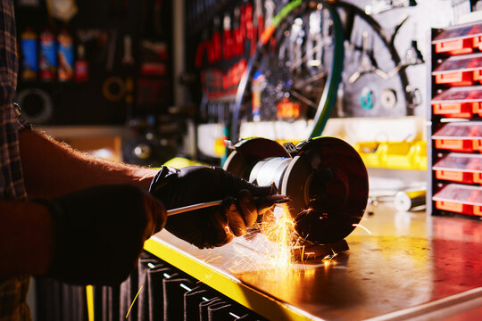 Mechanic sharpening tool with bench grinder in workshop