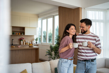 Happy couple enjoying morning coffee in modern apartment