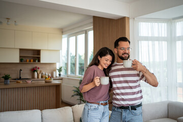 Happy couple drinking coffee and enjoying morning in modern apartment