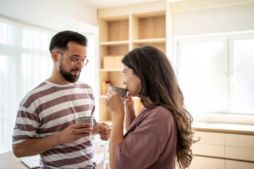 Young couple drinking coffee and having a serious conversation in their modern kitchen