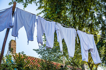 Colorful clothes drying on a line amidst lush green grass in a rural area during bright daytime