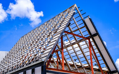 Construction progress of a building with exposed roof structure showcasing modern architectural design under clear blue sky