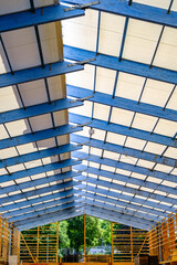 Construction progress of a building with exposed roof structure showcasing modern architectural design under clear blue sky