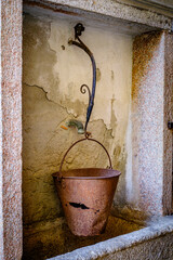 Historical stone fountain against a rustic wall in an Italian village, showcasing intricate craftsmanship and timeless charm in a serene setting