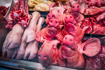 Freshly displayed pork cuts at a bustling market showcasing various meat parts and offal, attracting shoppers on a lively afternoon