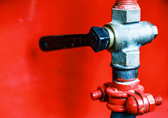 Close-up view of a vintage brass valve against a vibrant red background showcasing intricate design and craftsmanship
