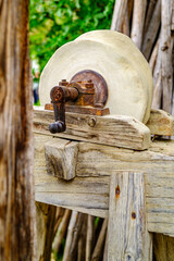 Historical stone wheel used for grinding grains in a rustic farming setting during daylight hours in an outdoor environment