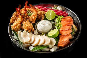 Grilled and raw seafood platter with shrimp, tuna, salmon, white fish, lime slices, dipping sauce,...