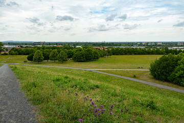 Weitblick vom Parkhügel mit grüner Landschaft, Wanderwegen und Blick auf die Stadt – ideal für Spaziergänge, Naturgenuss und Naherholung in urbaner Umgebung
