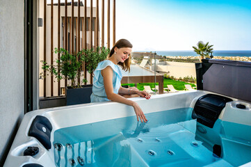 Travel moment with woman enjoying private rooftop jacuzzi with sea view. Luxury vacation lifestyle captured in peaceful outdoor setting.