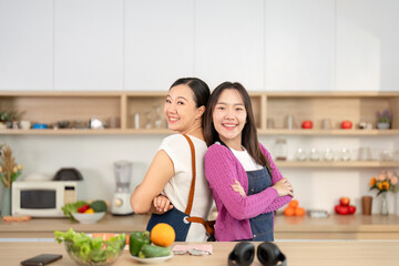 Empowerment and Togetherness. Two women posing back-to-back in a modern kitchen, celebrating friendship.